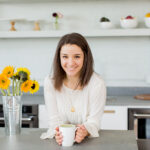 Photo of a woman with brown hair smiling in a kitchen.
